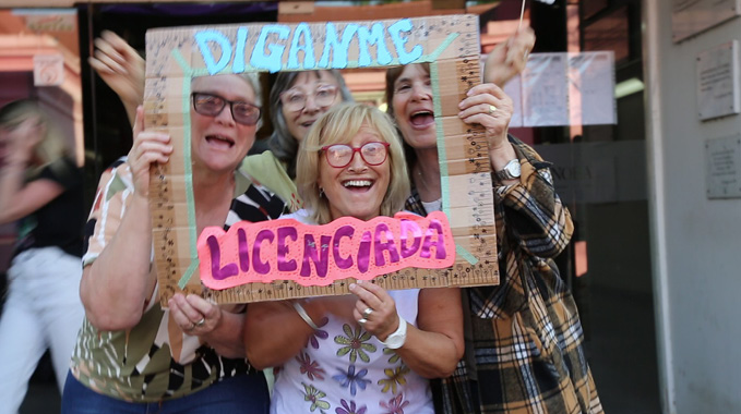 Un grupo de cuatro personas sonrientes sostiene un marco de cartón con las palabras "Dígame" y "Licenciada" escritas en colores azul y rosa.

Description generated by AI